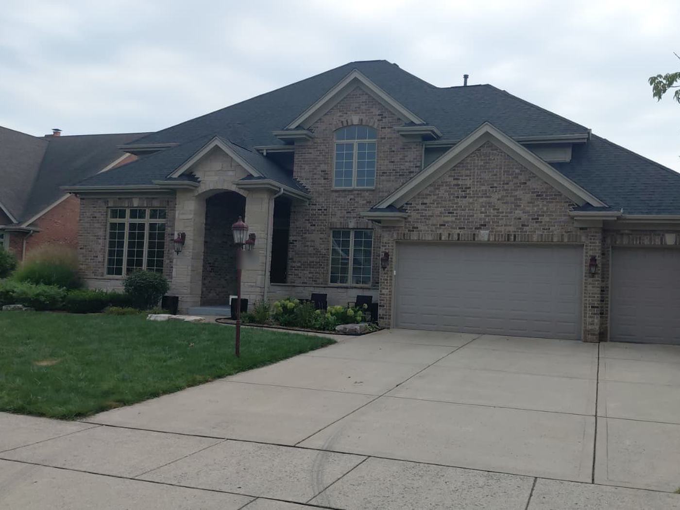 Brick two-story home in Munster with a new dark-gray roof and stone entry